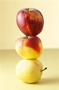 Three different apples balanced on top of each other