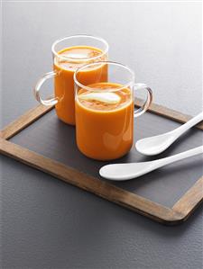 Curried tomato soup in two glass cups on a slate board