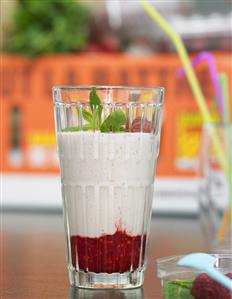 A glass of banana milkshake on raspberry puree