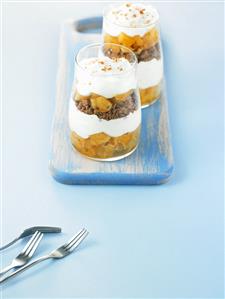 Layered dessert in glasses: pineapple, biscuits, soft cheese cream