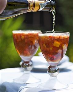 Summery champagne cocktail with peach and strawberries