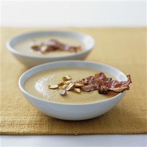 Two plates of peanut soup with fried bacon