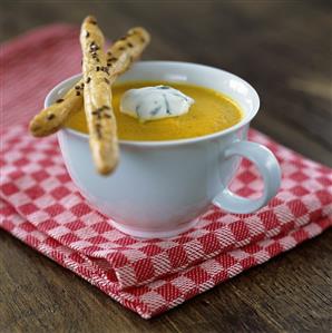 A cup of carrot soup with savoury puff pastry straws