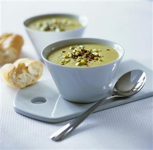 Cream of asparagus soup in two bowls with baguette