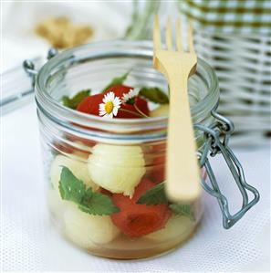 Melon salad with mint and daisies in preserving jar