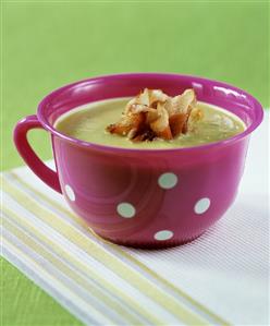 A cup of pea soup with fried ham