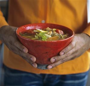 Man holding a bowl of Indian vegetable soup