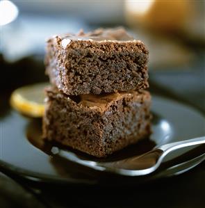 Two pieces of chocolate cake, stacked, on a plate