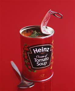 An opened tin of 'Heinz Tomato Soup' with pesto and spoon