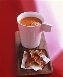 A cup of tomato soup with fried bacon