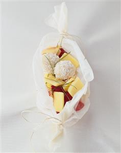 Mango with raspberries and coconut balls in baking parchment