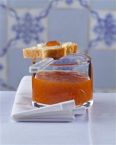 Jar of apricot jam with a slice of buttered brioche