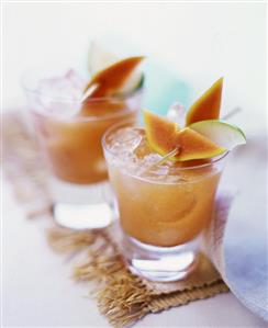 Two glasses of papaya and apple juice with ice cubes