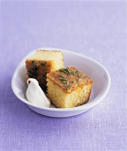 Two pieces of lemon and rosemary cake with clotted cream