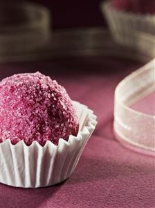 Chocolate coated in pink sugar in a paper case