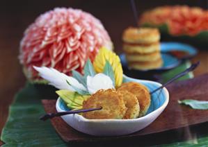 Three breaded medallions on skewers, carved fruit