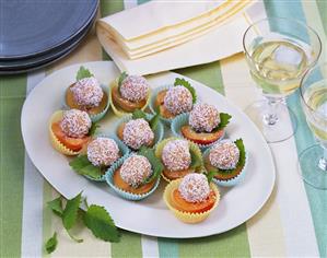 Apricots topped with coconut sweets in paper cases