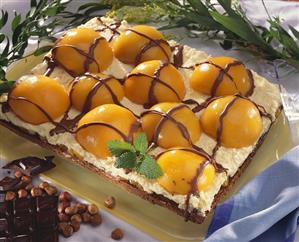 Chocolate nut cake topped with whipped cream and apricots