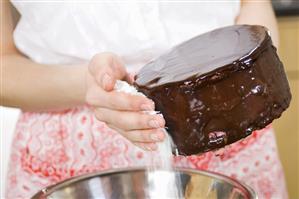 Sticking coconut flakes on the sides of a chocolate cake