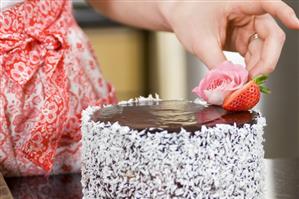 Decorating a chocolate cake with flowers and strawberries