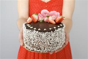 A chocolate cake decorated with flowers and strawberries