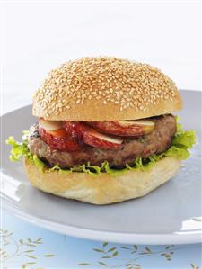 A pork burger with apple slices and lettuce