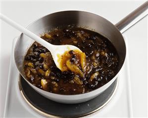 Lemon chutney in a pan with a cooking spoon