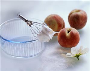 Still life with peaches, beaten egg white, whisk, sugar