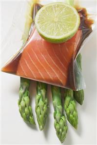 Vacuum-packed, marinated salmon fillet on asparagus