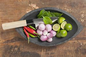 Limes, lime leaves, chillies and onions in a dish