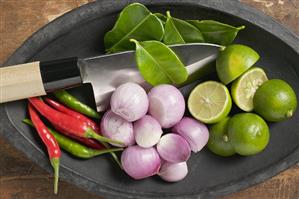 Limes, lime leaves, chillies and onions in a dish