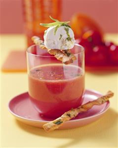 Cold tomato soup in glass with soft cheese ball, grissini
