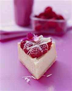 A piece of cheesecake with raspberries and white chocolate