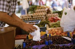 Market stallholder putting cherries into a bag