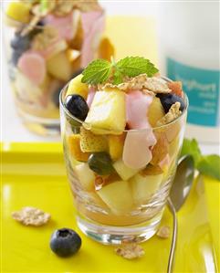 Fruit salad with berry yoghurt and cereal flakes in glass