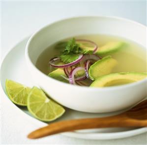 Avocado soup with lime wedges and coriander leaves