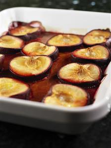 Plum halves in sauce in a baking dish