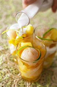 Pouring coconut milk over exotic fruit salad