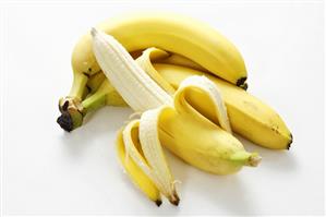 Half-peeled banana in front of small bunch of bananas