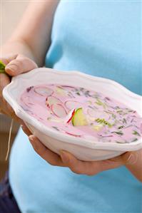 Woman holding a plate of cold beetroot soup