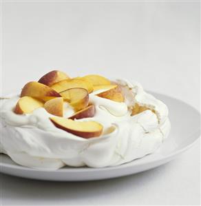 Pavlova with peach slices and cream