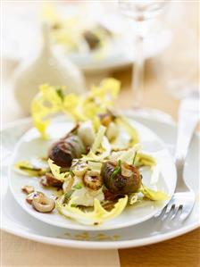 Dandelion salad with bacon-wrapped prunes and hazelnuts