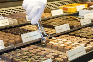 Chocolates with hand and tongs in a confectioner's display