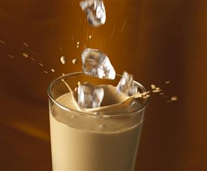 Ice cubes falling into a glass of chocolate liqueur