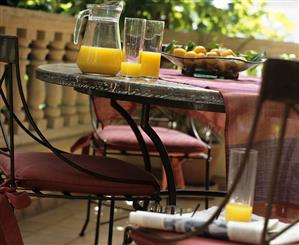 Orange juice and bowl of fruit on table on balcony