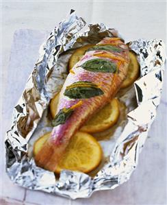 Red mullet with orange slices on aluminium foil