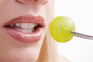 Young woman eating a grape