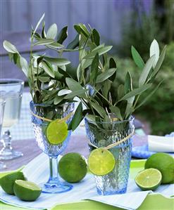 Bunches of olive branches in glasses decorated with lime slices