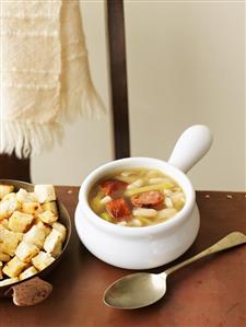 White bean and leek soup with sausage, croutons beside it