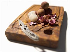 Lychees, some peeled, with knife on wooden board